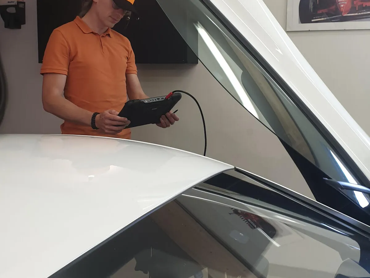 Diagnostik med surfplatta och OBD-utrustning i sportbil.